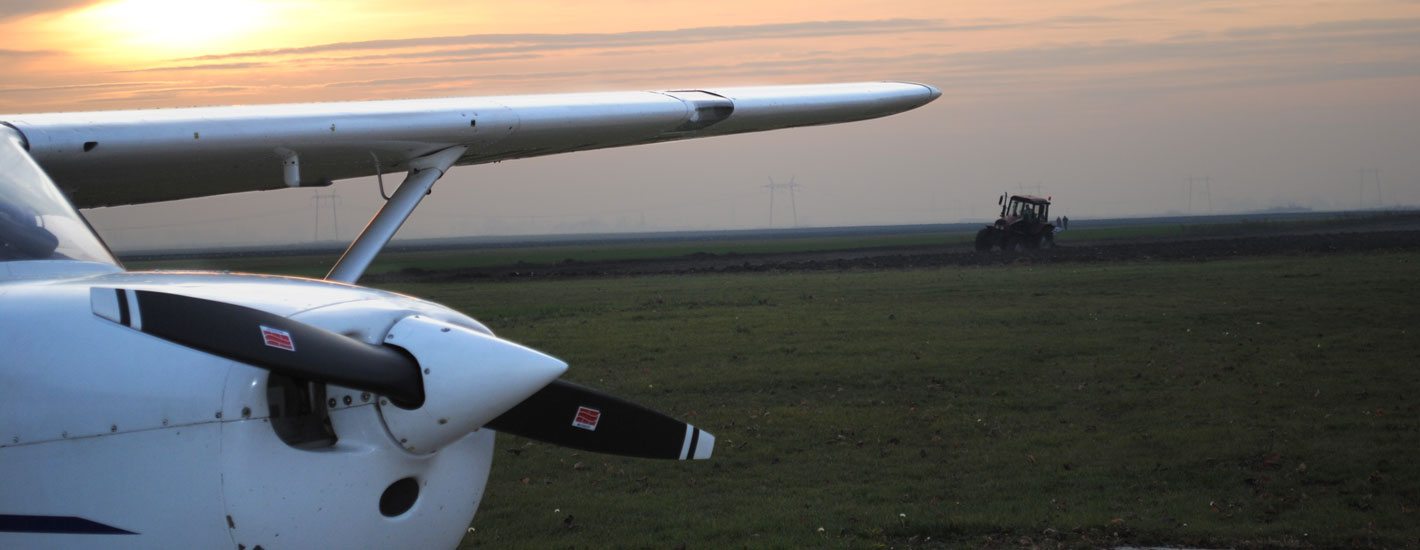 Cessna by a field at sunset