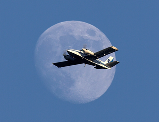 Piper Seneca flying in front of the moon